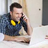 smiling-construction-worker-talking-on-mobile-phon-A8FGKY7